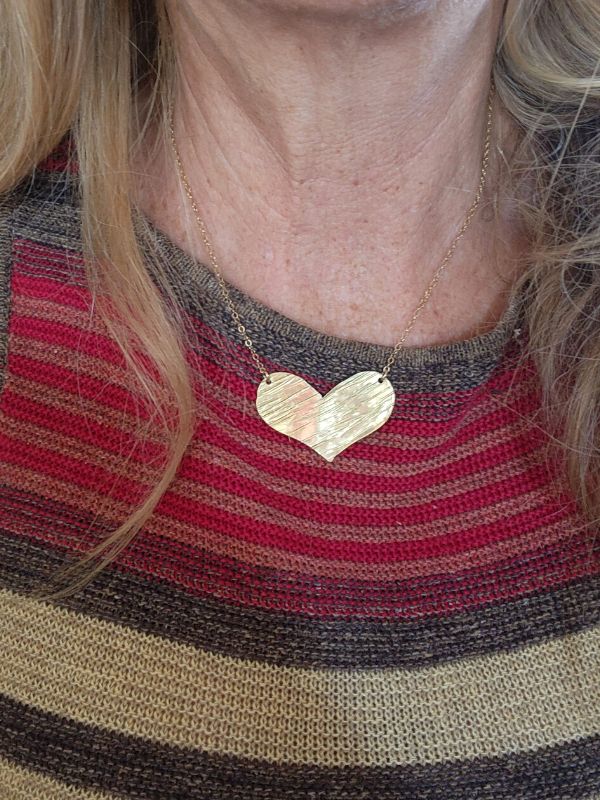 wearing gold textured heart necklace on earthy striped top